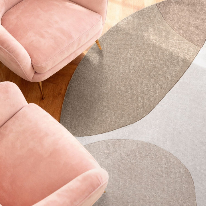Pink chairs with a gray and beige patterned rug on a wooden floor.