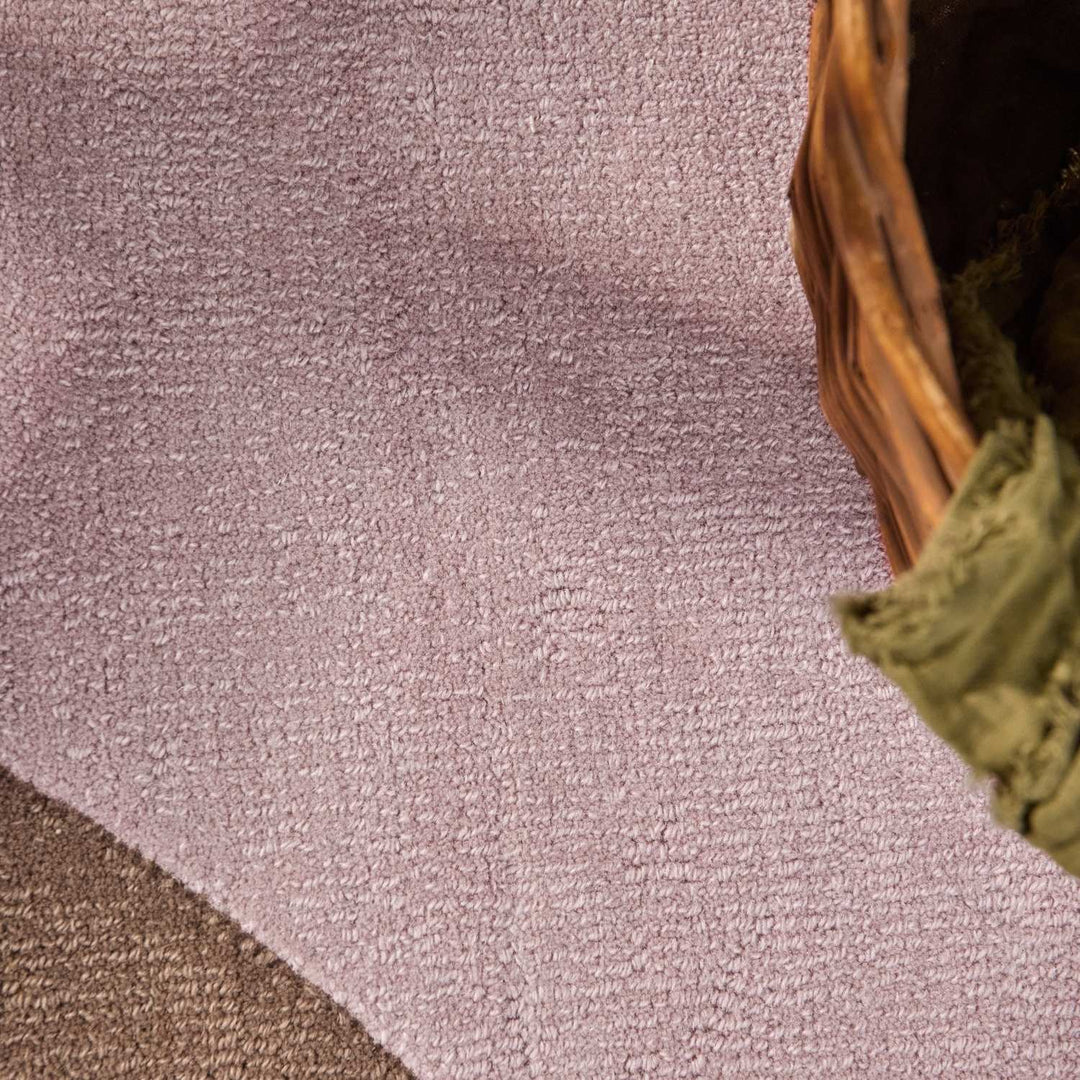 Close-up of a textured purple carpet with a woven basket corner.