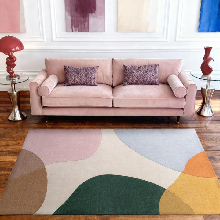 Pink sofa in a living room with a colorful abstract rug on the floor.