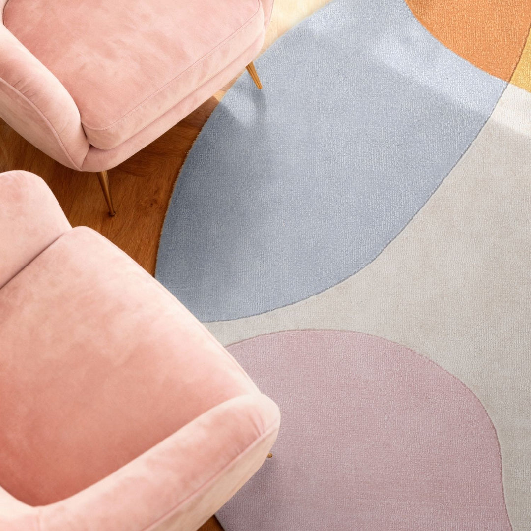 Colorful abstract rug with pink and beige chairs on a wooden floor