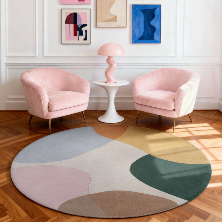 Two pink chairs and a colorful round rug in a room with abstract art on the walls.